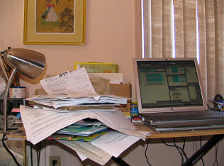 Stacks of paper pile up on the makeshift desk in my mother's spare bedroom, photograph copyright Lorelle VanFossen