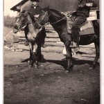 Melvin and Allen Knapp ride their horses in front of the Knapp family log cabin c1920s
